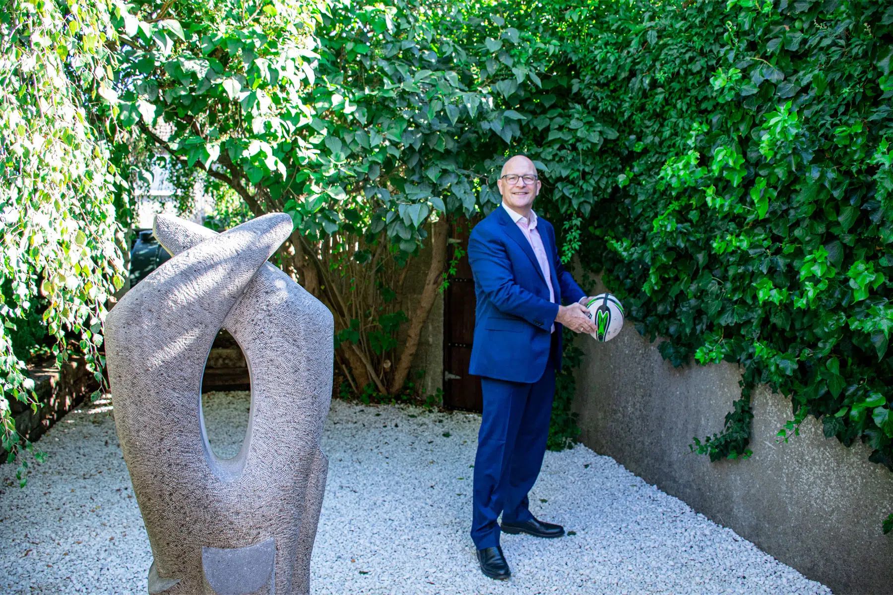John Griffin holding a rugby ball in the office garden.
